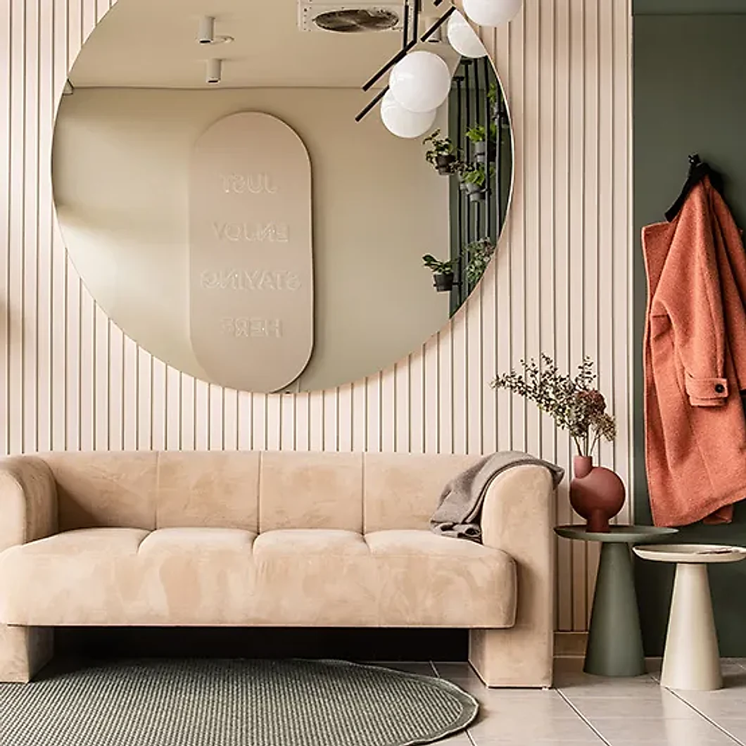 Die Lounge von Studio The BLISS: Rundspiegel, kannelierte Wand und ein Sofa in warmem Rosé
